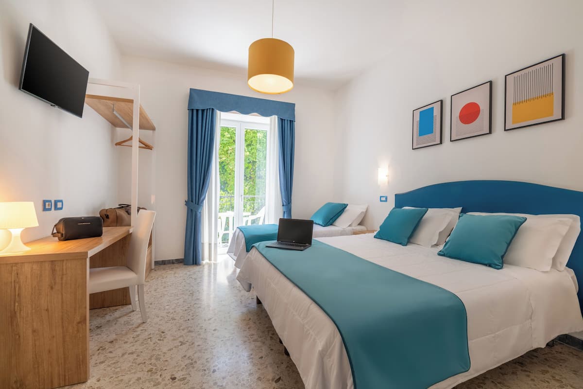 Habitación triple, balcón, vista al jardín | Minibar, caja de seguridad en la habitación y escritorio