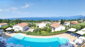 A resort with a swimming pool, lounge chairs, and a view of the sea. - Albergo Panoramica (Bardolino)