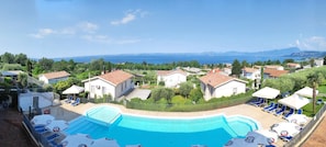 A resort with a swimming pool, lounge chairs, and a view of the sea.
