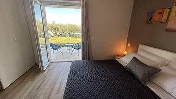 Een slaapkamer met een bed, nachtkastje, raam en uitzicht op de omgeving.