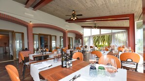 A restaurant with multiple tables set for dining, featuring a brick archway and wooden ceiling beams. - Albergo Panoramica (Bardolino)