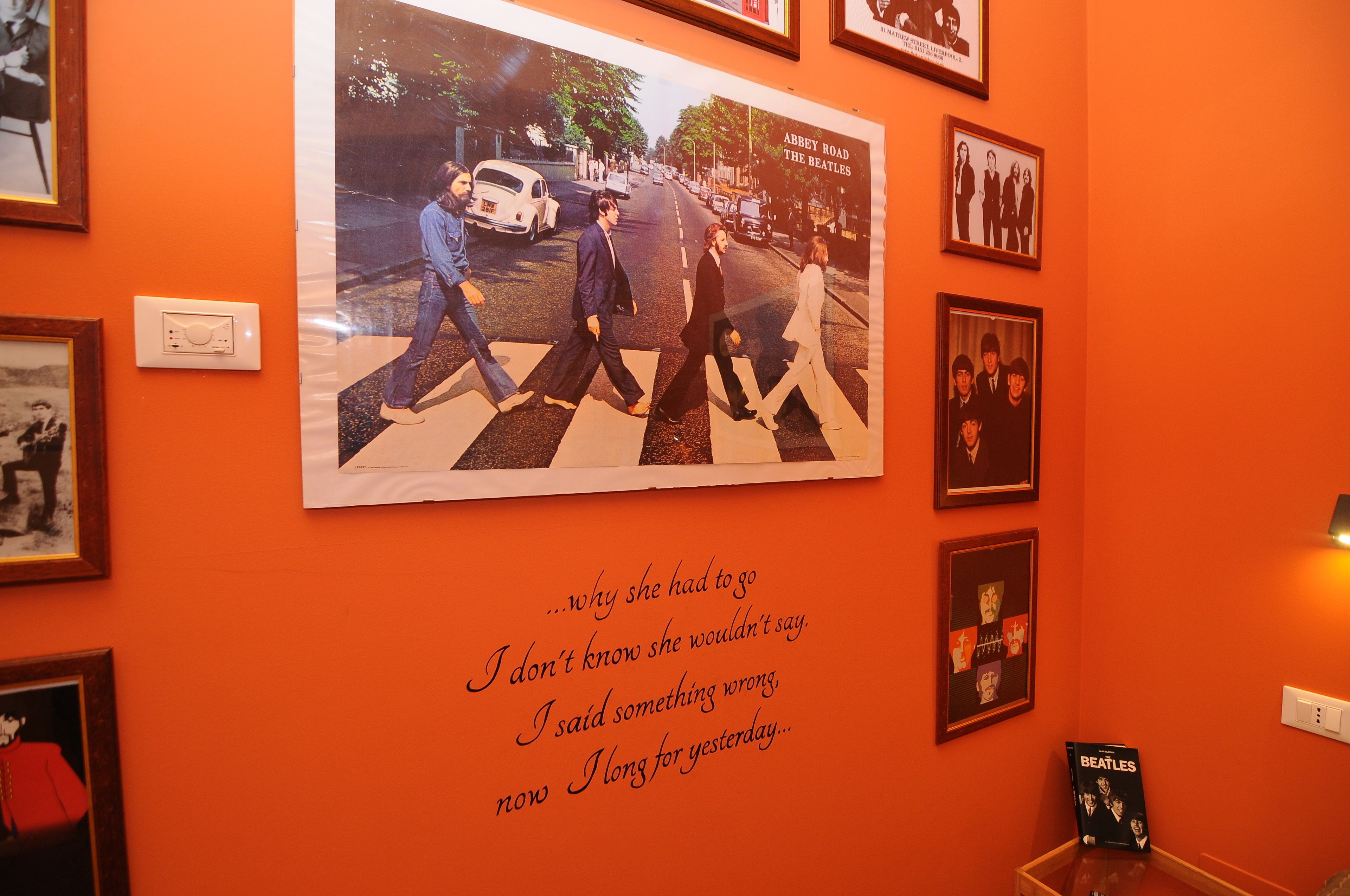 Una pared con cuadros enmarcados y un cartel de los Beatles.