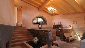 Un interior acogedor con chimenea de piedra, escalera de madera y un espacio de estar confortable.