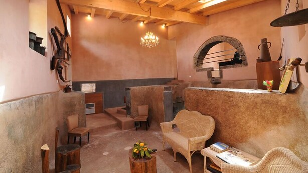 Un interior rústico con vigas de madera, chimenea de piedra y muebles de mimbre.