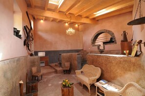 A rustic interior with wooden beams, a stone fireplace, and wicker furniture. - Il Giardino degli Ovali (Fiumefreddo di Sicilia)