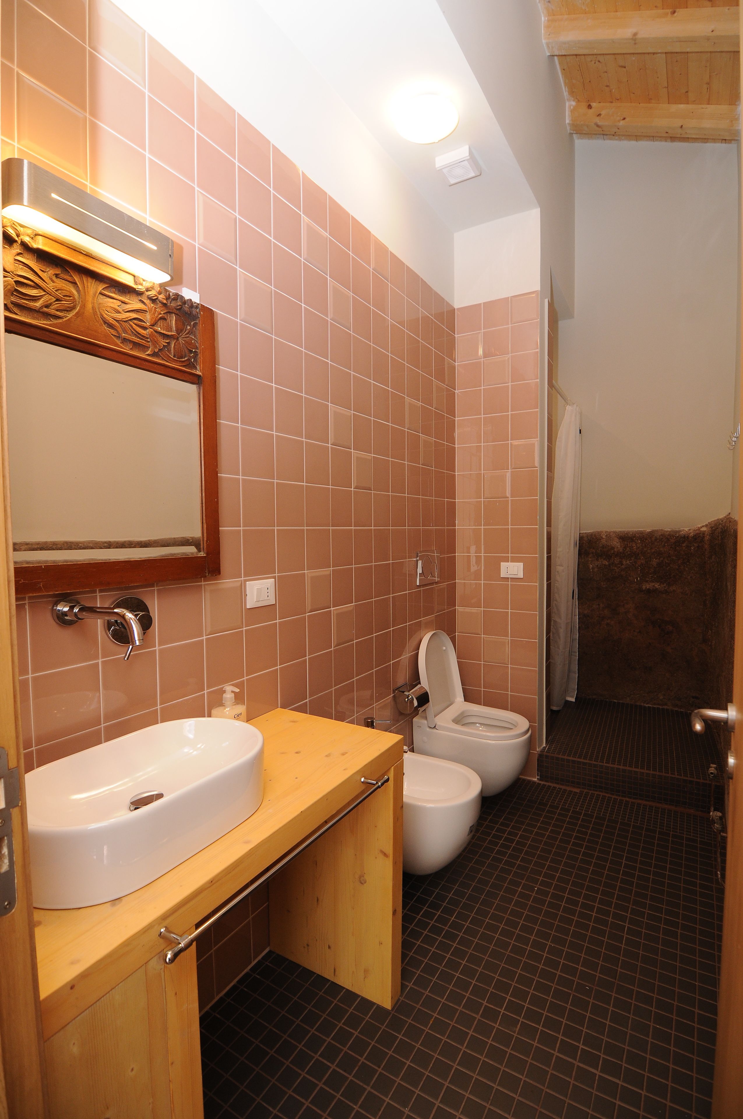 A bathroom with a wooden vanity, a sink, a toilet, and a shower area.