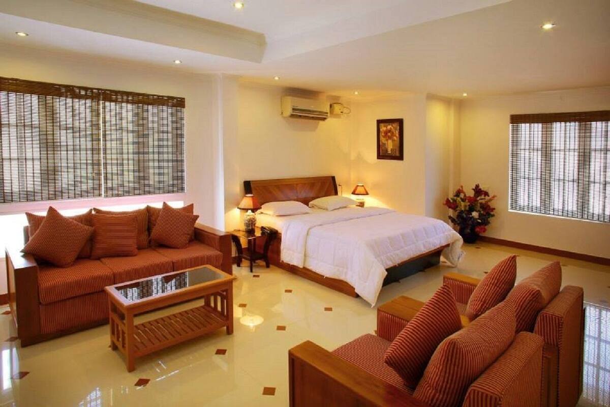 Une chambre d’hôtel avec un grand lit, deux canapés, une table basse et une petite table avec une lampe.