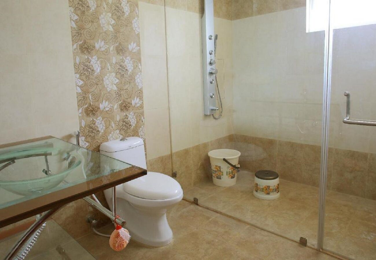 Een badkamer met een douchecabine van glas, een toilet en een glazen wastafel.