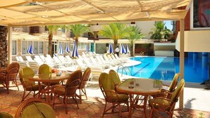 A poolside area with lounge chairs and umbrellas, a pool, and a covered seating area. - Çınar Family Suite Hotel (Manavgat)