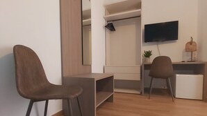 Una habitación moderna con literas, un escritorio, una silla, un televisor y una planta pequeña.