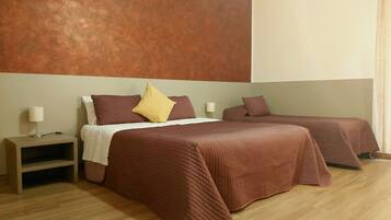 Una habitación de hotel con dos camas, una mesita de noche y un aire acondicionado instalado en la pared.