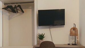 Un dormitorio moderno con cama, escritorio, silla, televisión y un refrigerador pequeño.