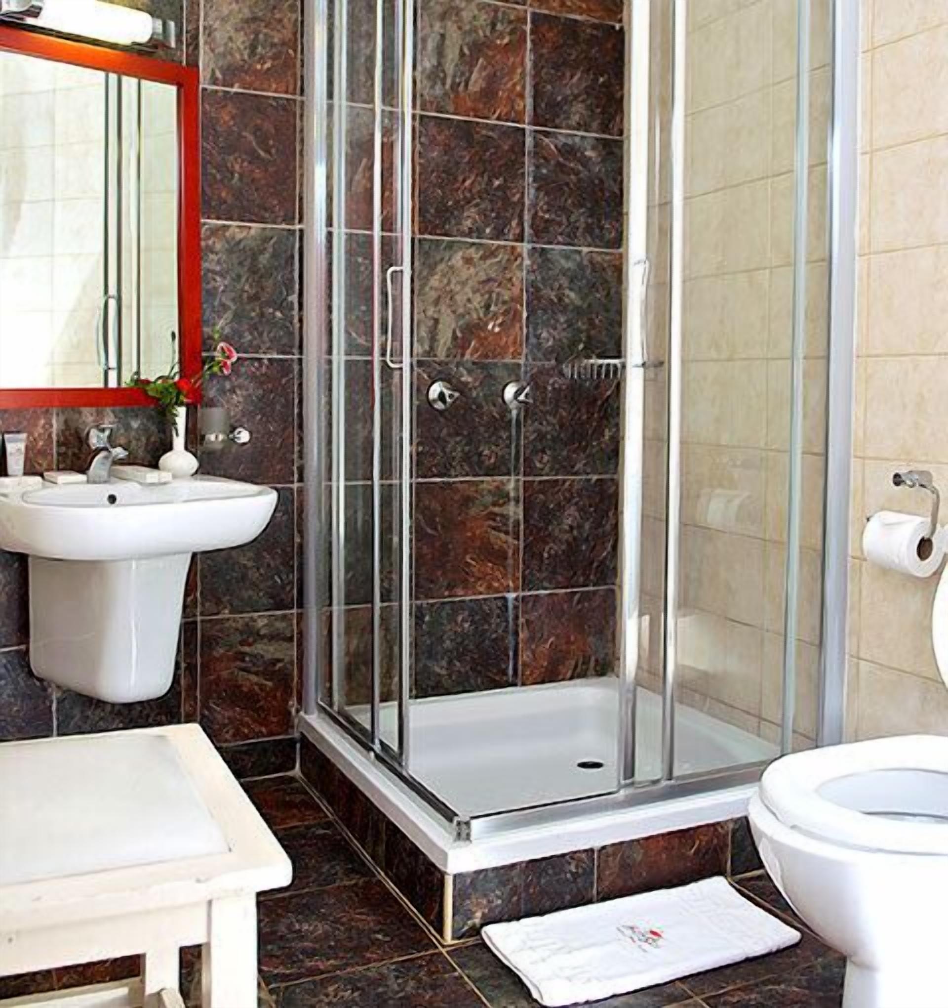 A bathroom with a glass shower enclosure, a sink, and a toilet.