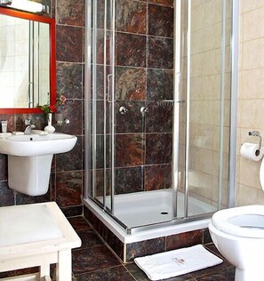 A bathroom with a glass shower enclosure, a sink, and a toilet.