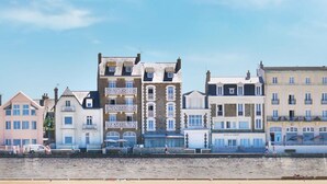 A row of coastal buildings with varying architectural styles, including a prominent building with a sign that reads "HOTEL LA ARM." - Hôtel L'Antinéa (Saint-Malo)