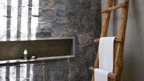 Een stenen muur met een ingebouwd schap en een houten ladder die ertegenaan staat.