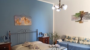A bedroom with a bed, bedside tables, a lamp, a plant, and artwork on the walls. - B&B Le Quattro Stagioni (Agrigento)