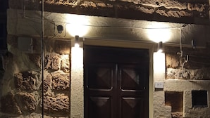 A stone building with a dark wooden double door, illuminated by overhead lights. - B&B Le Quattro Stagioni (Agrigento)