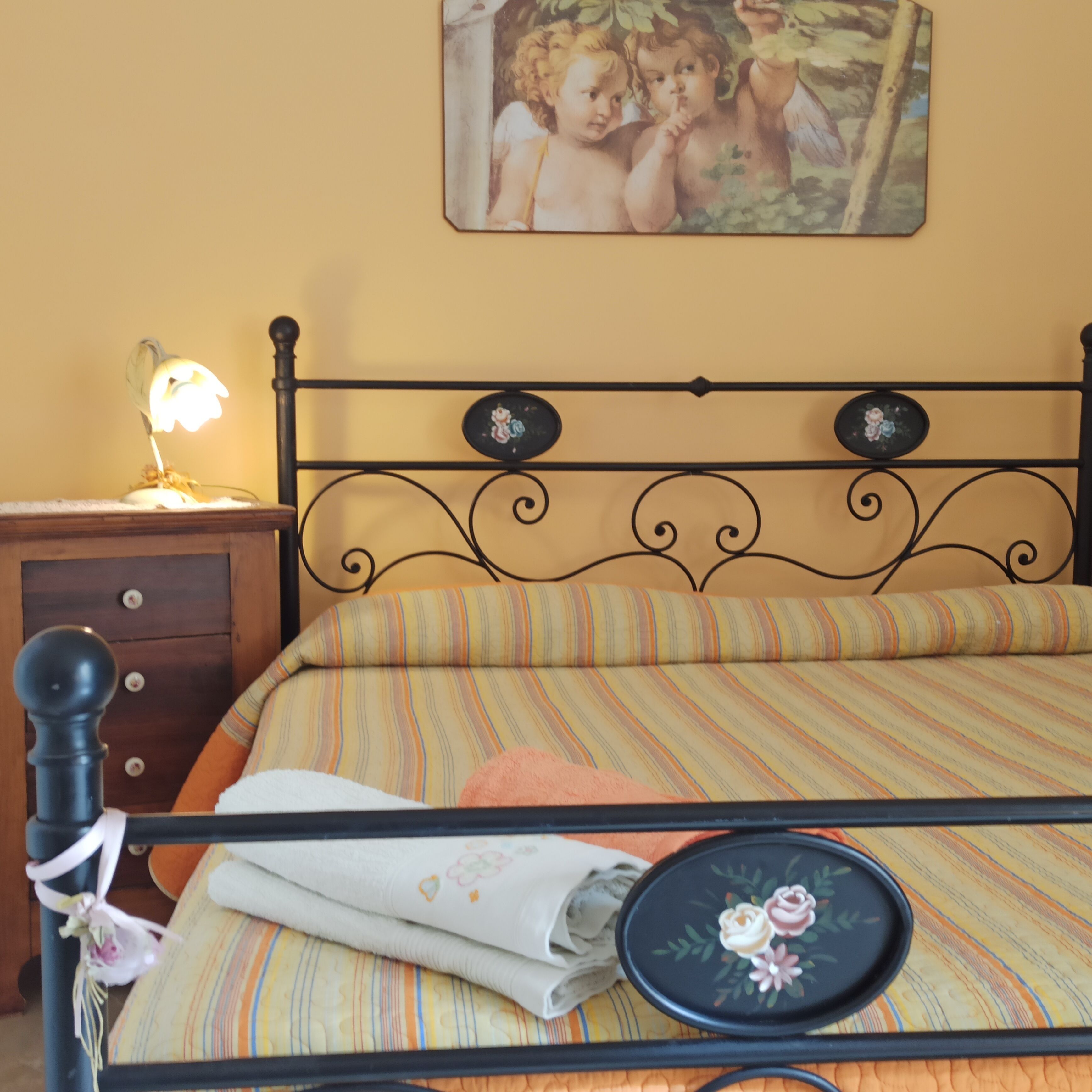 A bed with a striped bedspread, a nightstand with a lamp, and a wall-mounted picture.