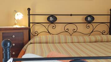 A bed with a striped bedspread, a nightstand with a lamp, and a wall-mounted picture.
