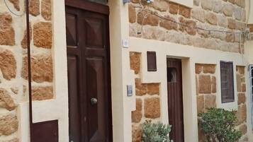 A stone building with a brown door and potted plants.