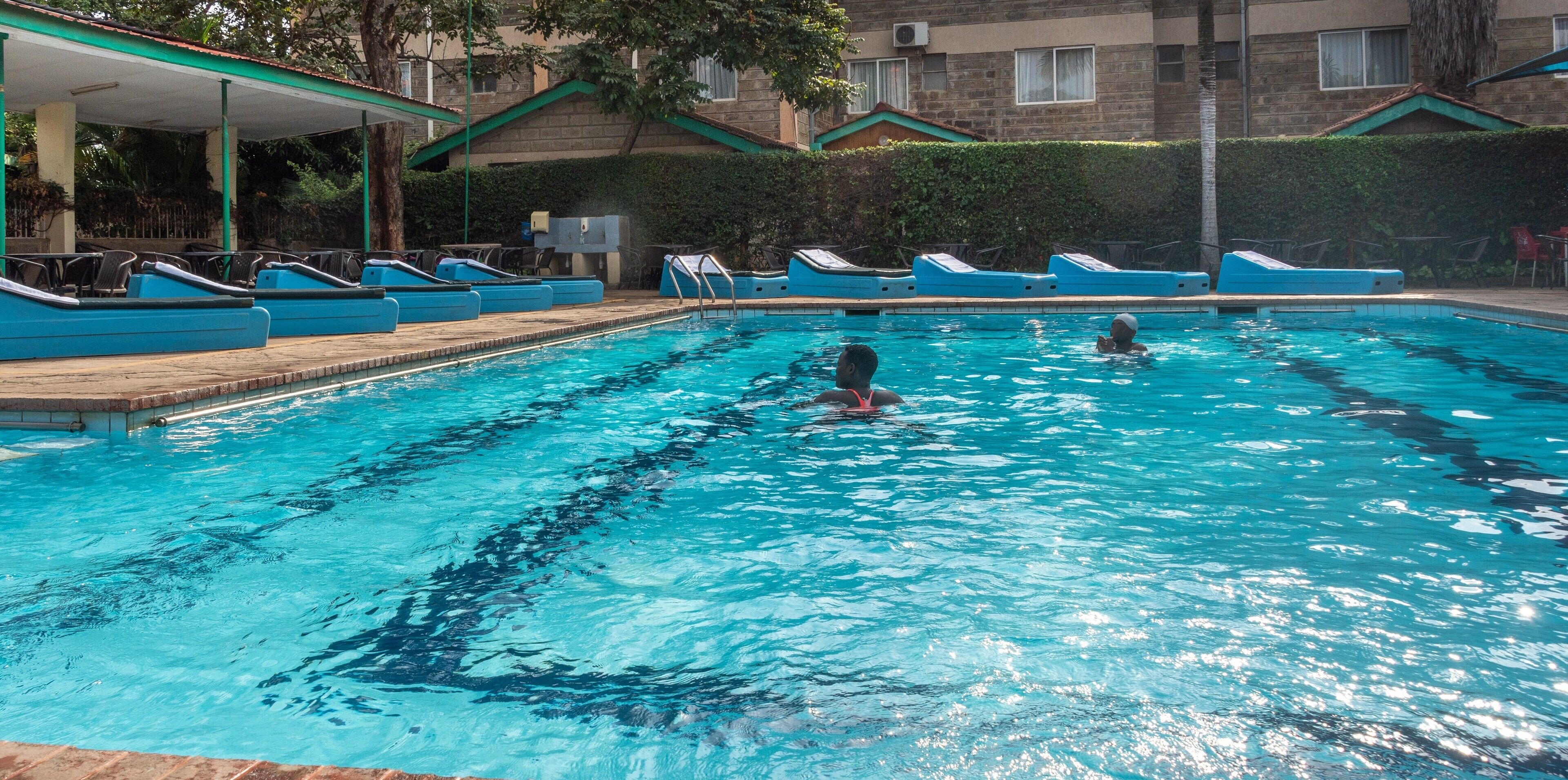 A swimming pool with lounge chairs and a covered area.