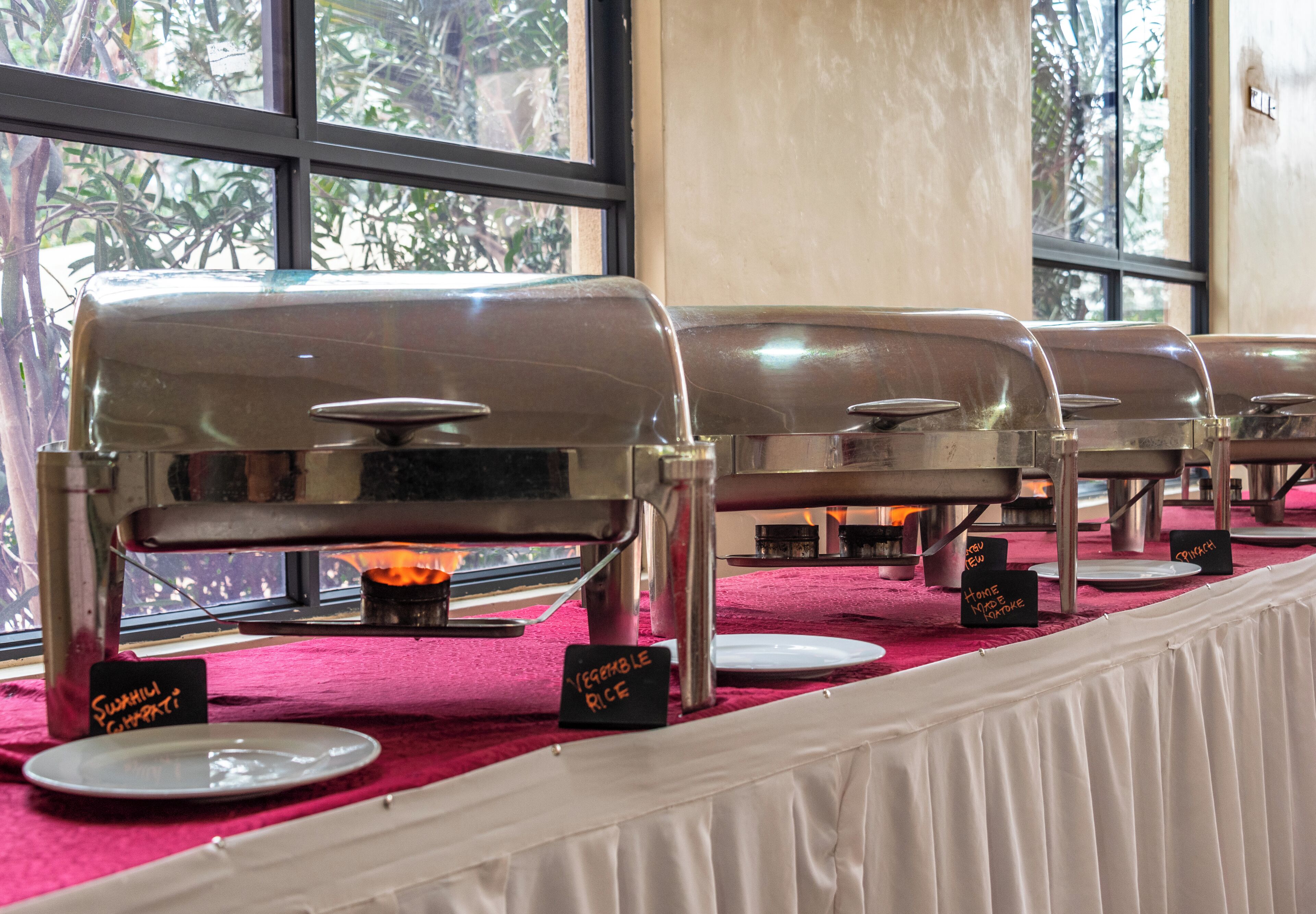 A buffet setup with a grill station and labeled dishes.