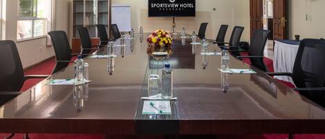 A conference room with a long table, chairs, water bottles, and a floral centerpiece.