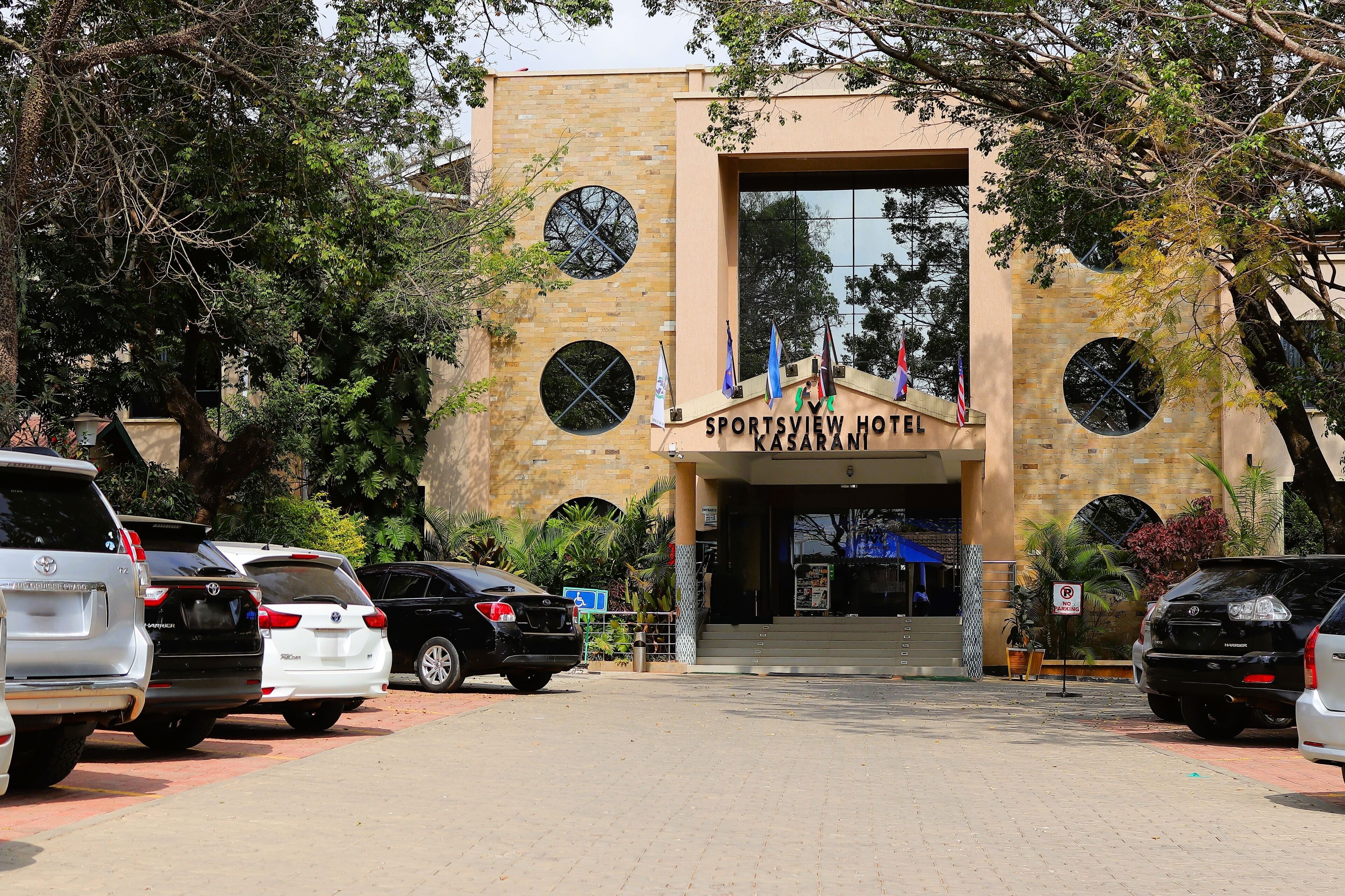 The entrance to Sportsview Hotel with a brick facade, multiple windows, and flags.