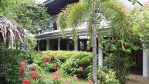 A traditional house with a covered porch, surrounded by lush greenery and flowering plants. - SunzEn Palawan, Resort (Sunz En Coron Resort) (Coron)