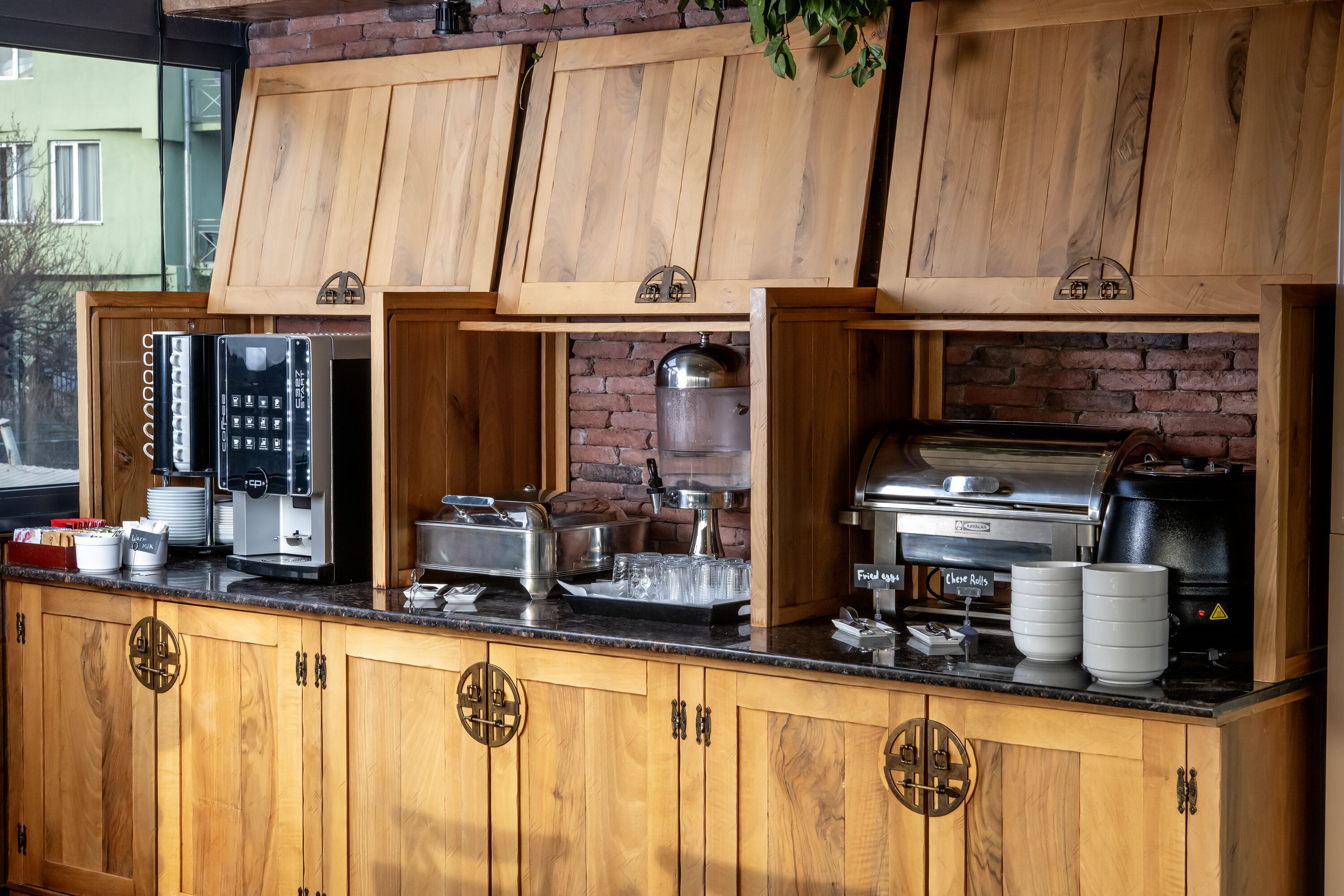A buffet setup with wooden cabinets, a brick wall, and various food service equipment.