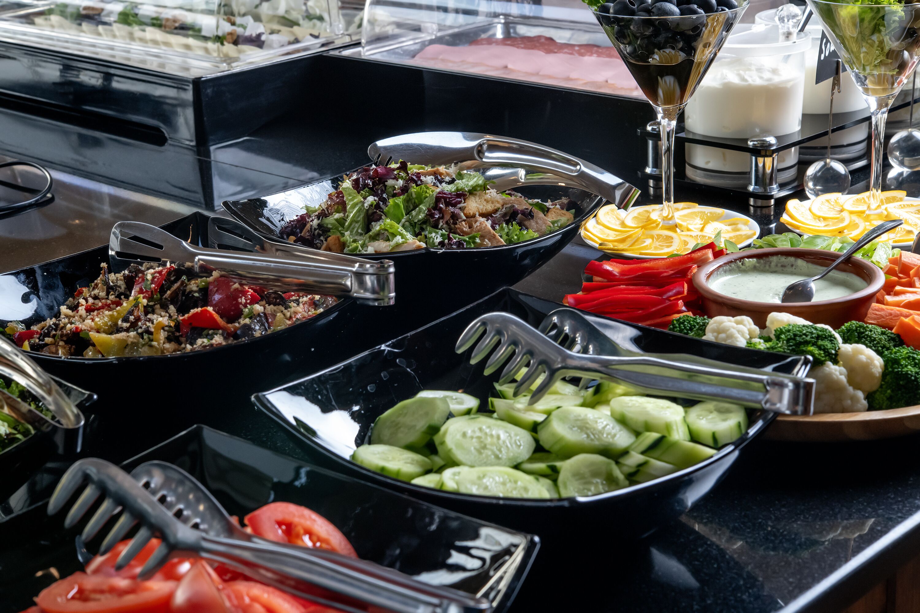 A buffet with various food options including salads, vegetables, and dips.