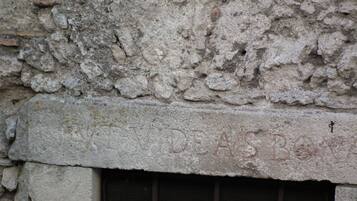 A stone wall with a window featuring a metal grille.