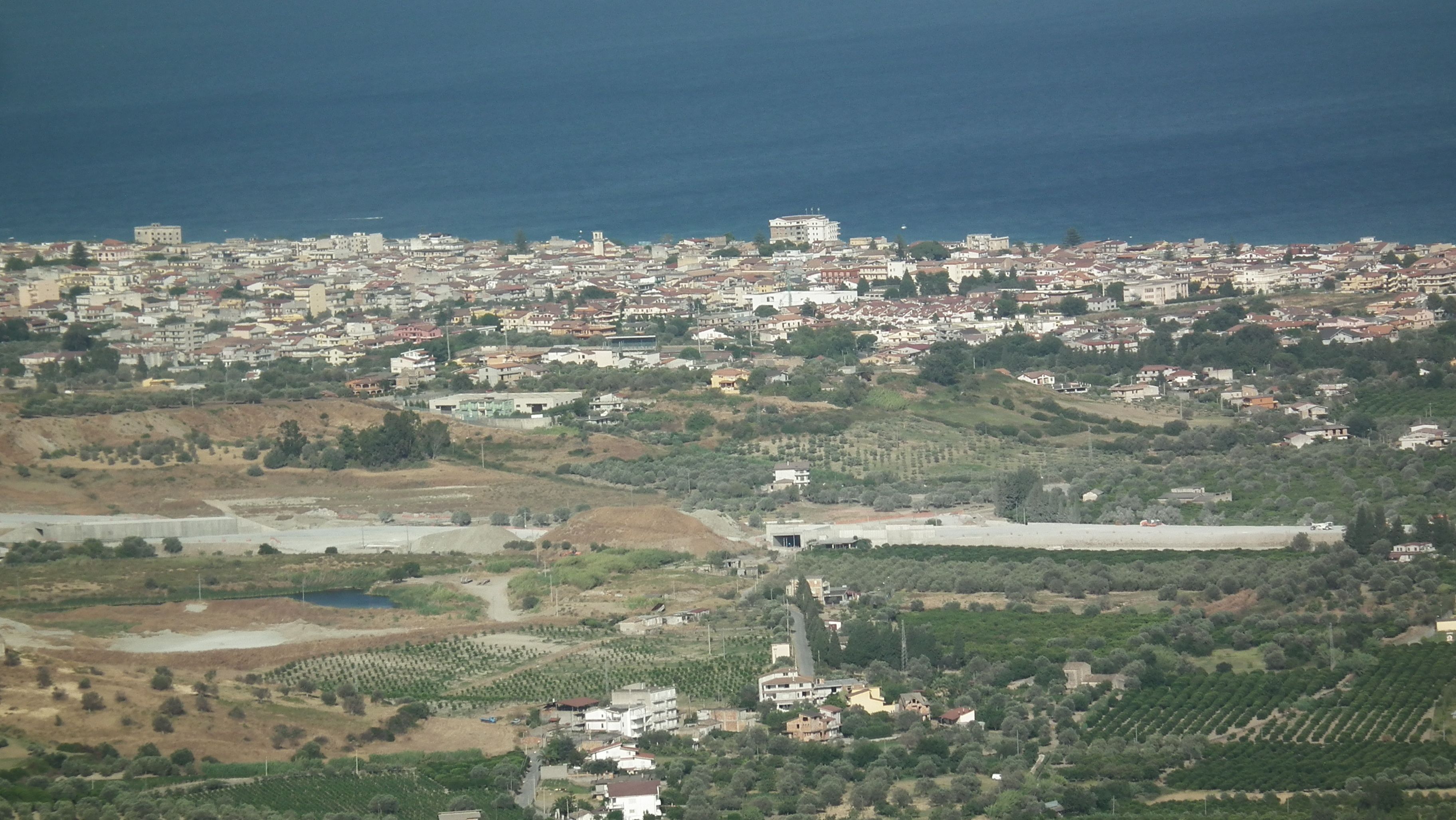 A coastal town with a mix of residential buildings and vineyards.
