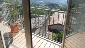 Un balcon agrémenté d’un pot de fleurs, un sol carrelé et une vue sur un paysage lointain.