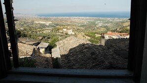 Une vue depuis une fenêtre donnant sur un paysage côtier, avec des bâtiments et un ciel dégagé.