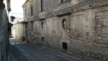 A narrow cobblestone street flanked by old stone buildings with arched windows and doorways.