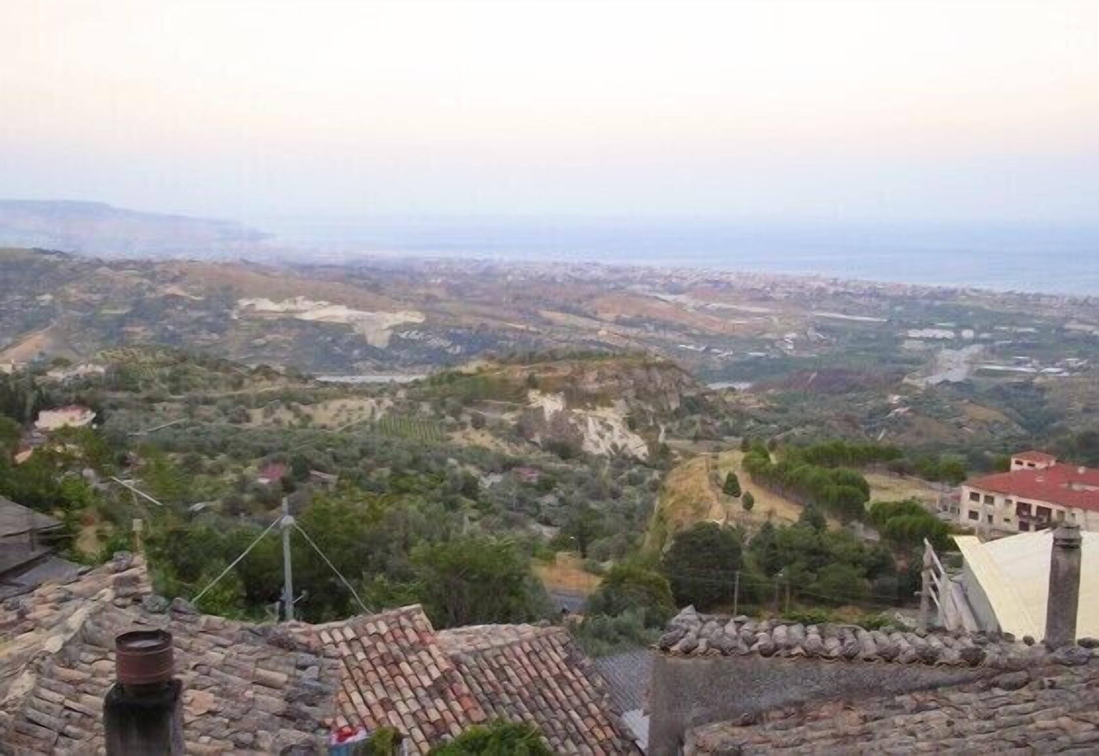 Une vue d’un paysage vallonné, avec des bâtiments au premier plan.