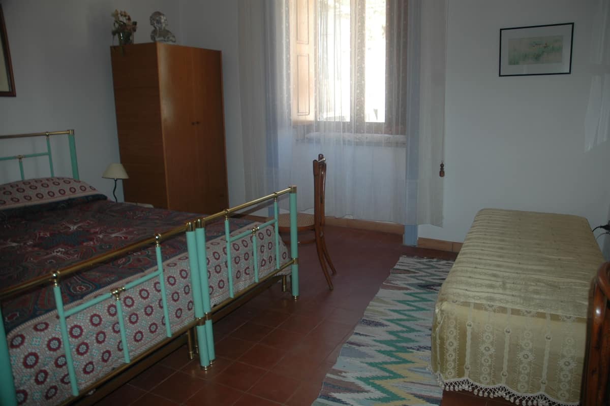 Un dormitorio con cama, armario, ventana con cortinas y alfombra.
