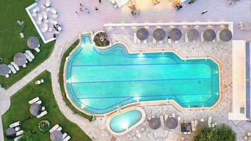 Eine Vogelperspektive eines Schwimmbeckens mit umliegenden Liegebereichen und einem kleinen, angrenzenden Pool.