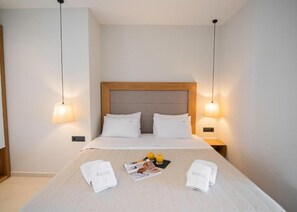 Una habitación de hotel con una cama bien hecha, dos lámparas de noche y una revista sobre la cama.