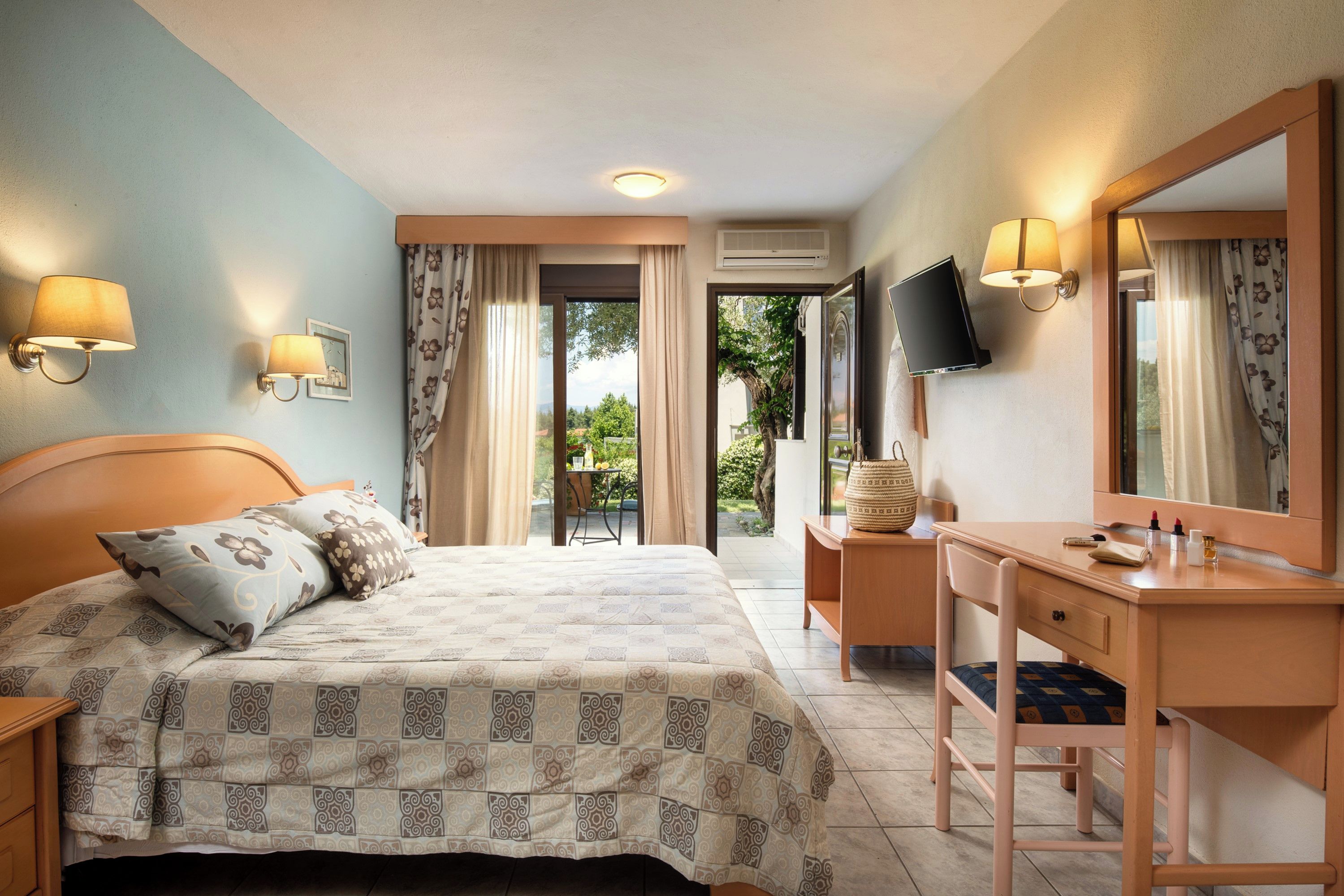 A hotel room with a bed, a desk, a chair, a TV, and a window with curtains.