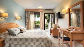 A hotel room with a bed, a desk, a chair, a TV, and a window with curtains.