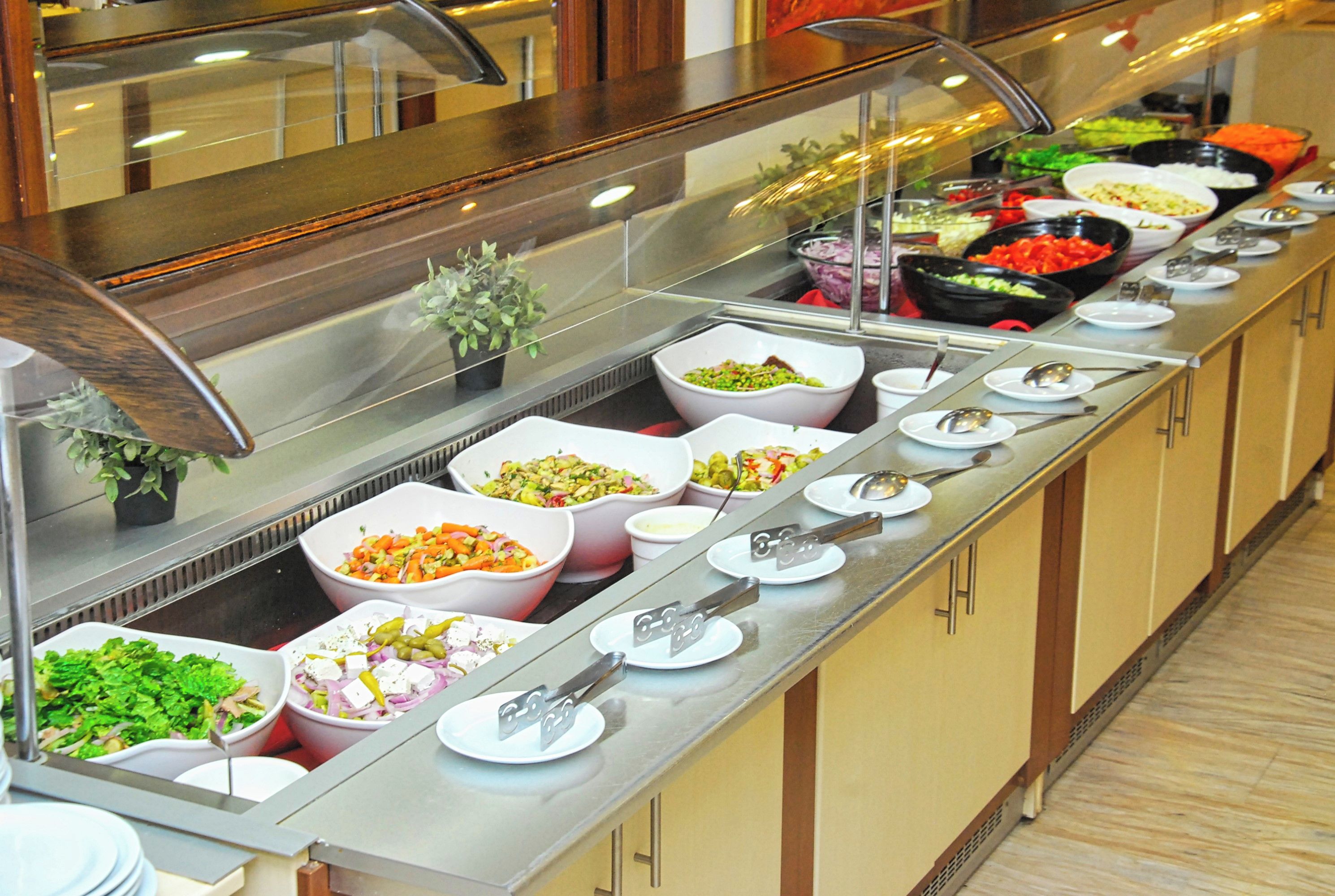 A buffet line with various food options, including salads, vegetables, and meats.