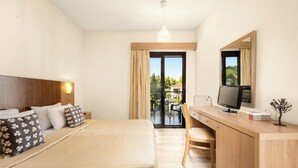 A hotel room with a bed, a desk, a chair, a TV, and a view of the outdoors. - Chrousso Village (Kassandra)