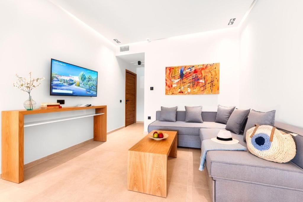 Una sala de estar moderna con un televisor de pantalla plana, una mesa de centro de madera, un sofá gris y un cuadro abstracto de colores vivos.