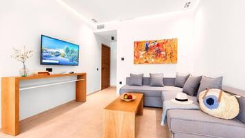 Una sala de estar moderna con un televisor de pantalla plana, una mesa de centro de madera, un sofá gris y un cuadro abstracto de colores vivos.