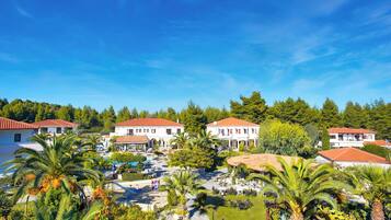 Un resort con varias construcciones, piscina y abundante vegetación.