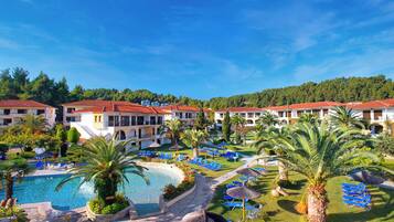 Un resort con piscina, sillas de descanso y montañas al fondo.