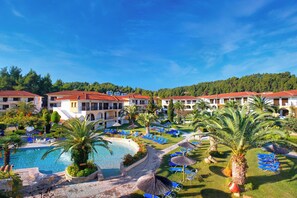 Un resort con piscina, sillas de descanso y montañas al fondo.